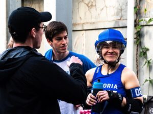 A Victorian Roller Derby League skater caught mid event. Realising the photo caught them, smiling sheepishly.
