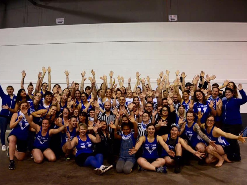 An entire Victorian Roller Derby League photo at The Great Southern Slam tournament with everyone's arms in the air excited!