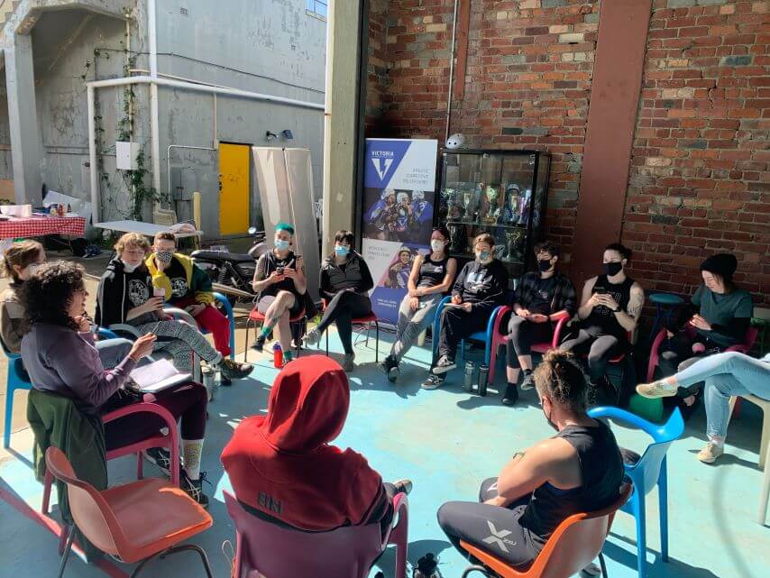 Skaters sitting in a circle doing a bootcamp and talking about strategy and other exciting derby things.